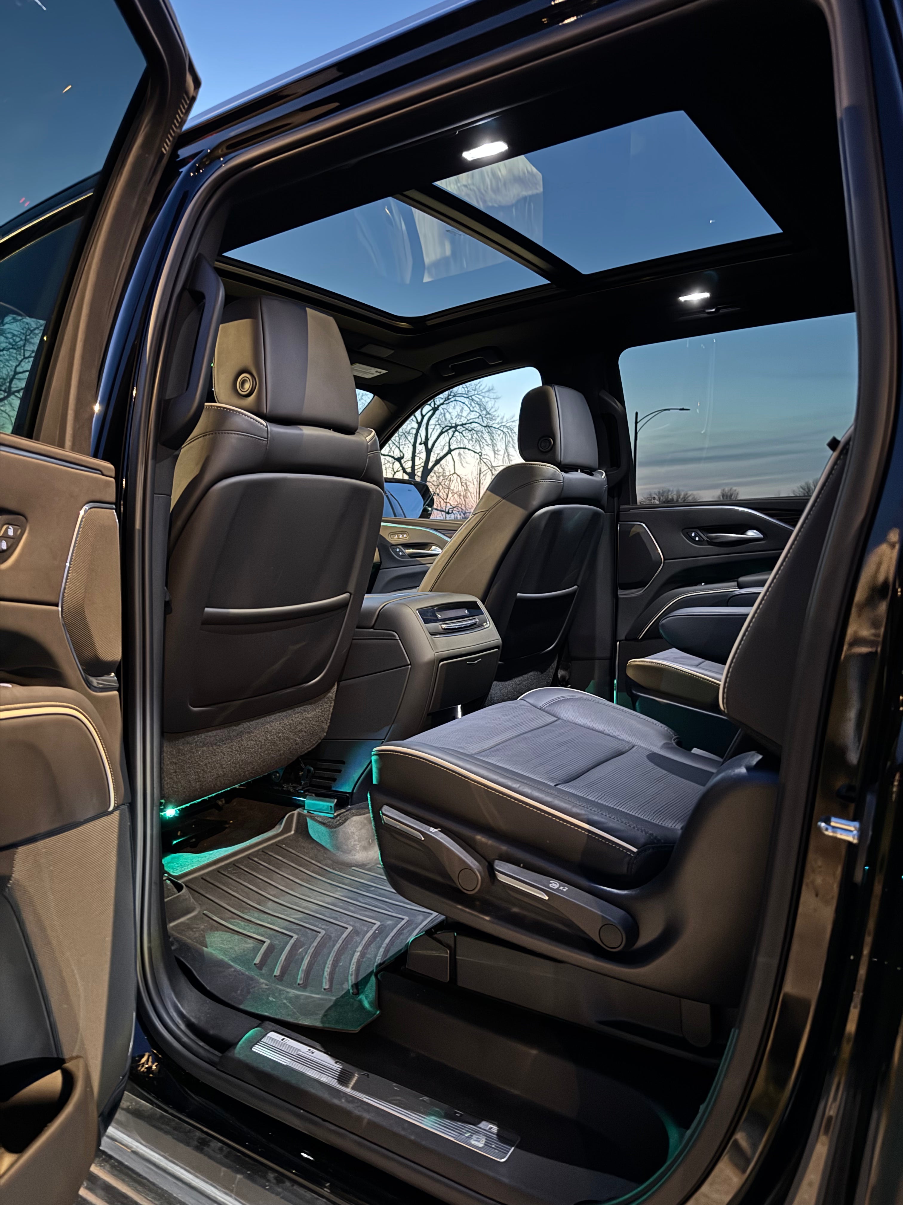 Cadillac Escalade interior view from back seats to front, highlighting the panoramic sunroof, advanced dashboard, and premium leather finishes.