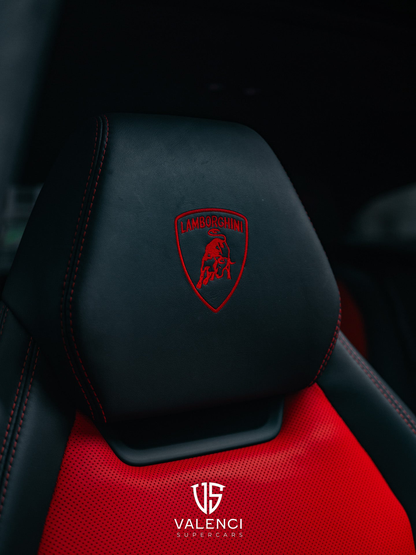 Lamborghini Urus close-up of premium black leather seat featuring a red Lamborghini logo, showcasing luxury craftsmanship and attention to detail.